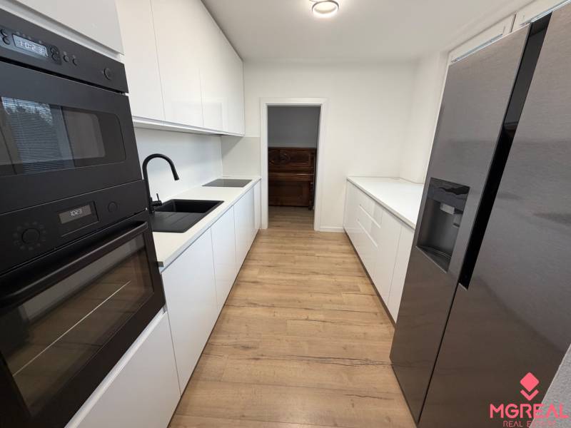 3 izbový byt s balkónom Topoľčany / PRENAJOM  - Kuchyňa s bielymi skrinkami, čiernymi spotrebičmi a podlahou s dreveným dekorom v 3-izbovom byte.