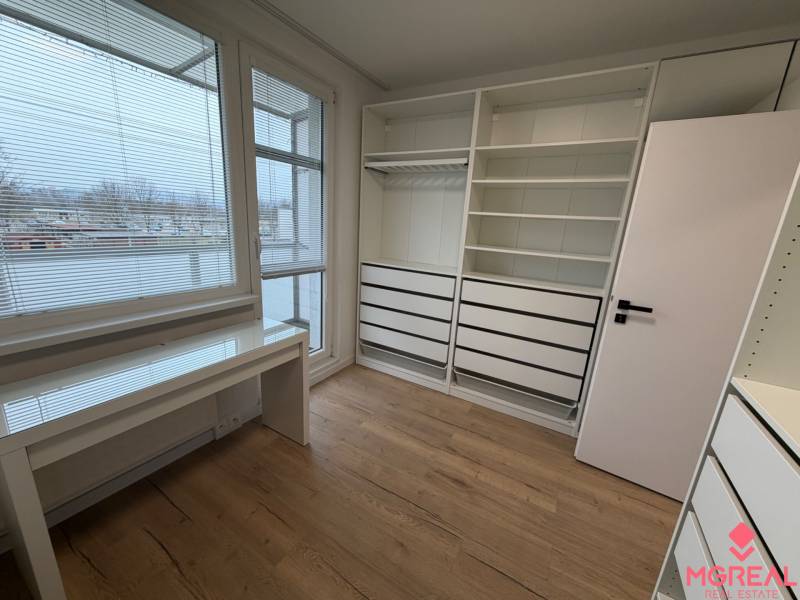 3 izbový byt s balkónom Topoľčany / PRENAJOM  - Izba v 3-izbovom byte s poličkami, stolom a podlahou s dreveným dekorom.