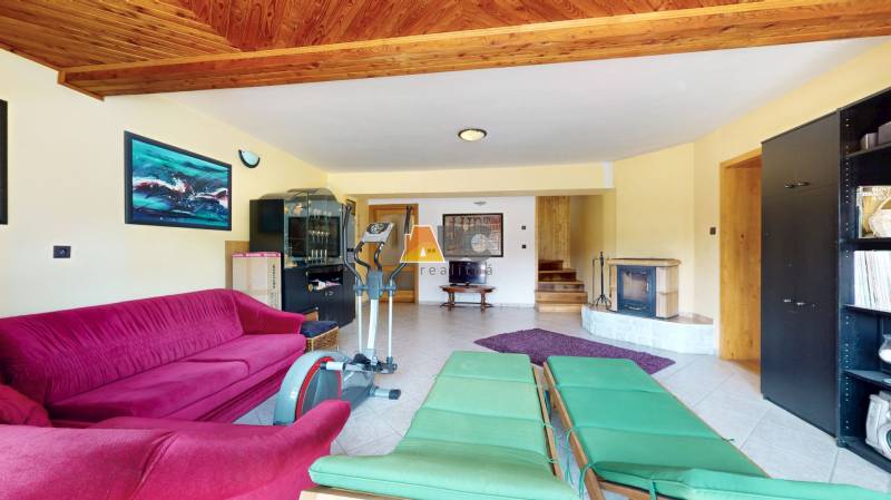 Na predaj Rodinný dom -rezort - Banská Bystrica 4500m2 - Obývacia izba v rodinnom dome s krbom, nábytkom a cvičebným zariadením.