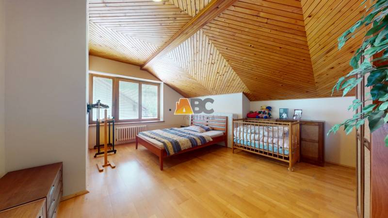 Na predaj Rodinný dom -rezort - Banská Bystrica 4500m2 - Podkrovná izba v rodinnom dome s dreveným stropom, detskou postieľkou a posteľou.