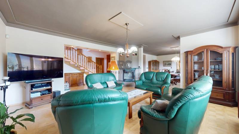 Na predaj Rodinný dom -rezort - Banská Bystrica 4500m2 - Obývacia izba v rodinnom dome so zeleným sedacím súpravom a dreveným nábytkom.