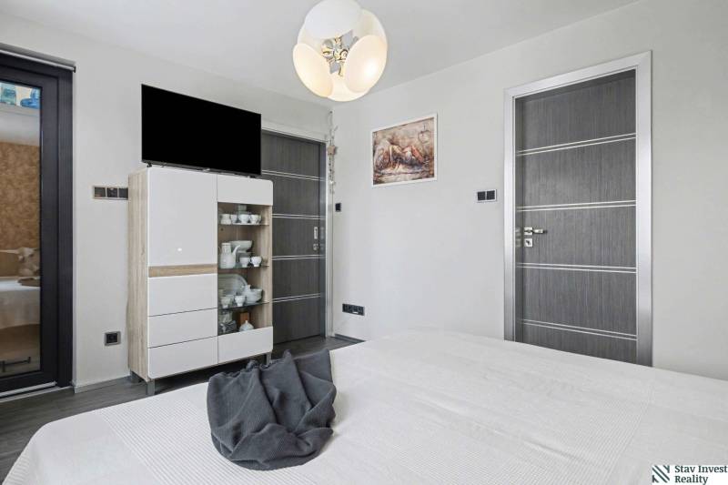 Ideálny dom pre rodinu, Blatné, okr. Senec - Spálňa v rodinnom dome s nábytkom, televízorom a dekoračným osvetlením.