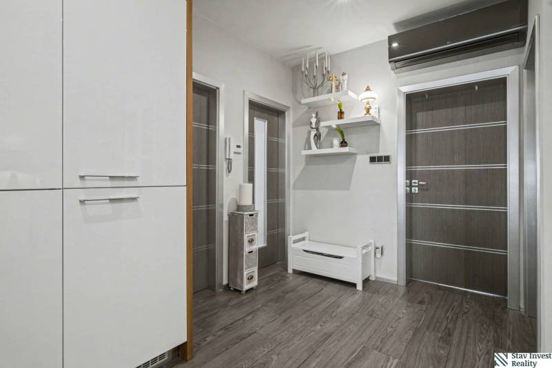 Ideálny dom pre rodinu, Blatné, okr. Senec - Chodba v rodinnom dome s vešiakmi, bielym nábytkom a podlahou s dreveným dekorom.