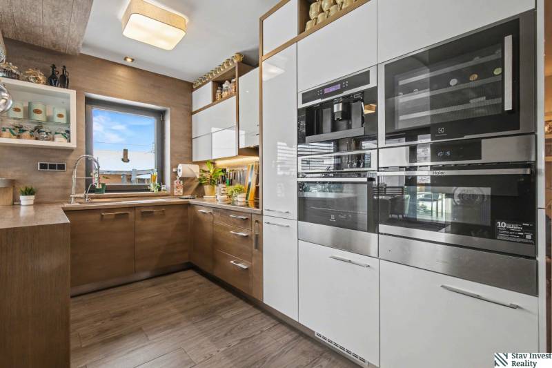 Ideálny dom pre rodinu, Blatné, okr. Senec - Kuchyňa v Rodinnom dome s podlahou s dreveným dekorom a modernými spotrebičmi.