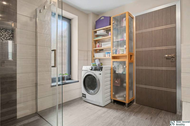 Ideálny dom pre rodinu, Blatné, okr. Senec - Kúpeľňa v rodinnom dome s práčkou, sprchovým kútom a podlahou s dreveným dekorom.