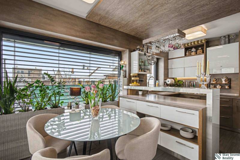 Ideálny dom pre rodinu, Blatné, okr. Senec - Jedálenský kút v rodinnom dome s preskleným stolom, rastlinami a kuchynským príslušenstvom.