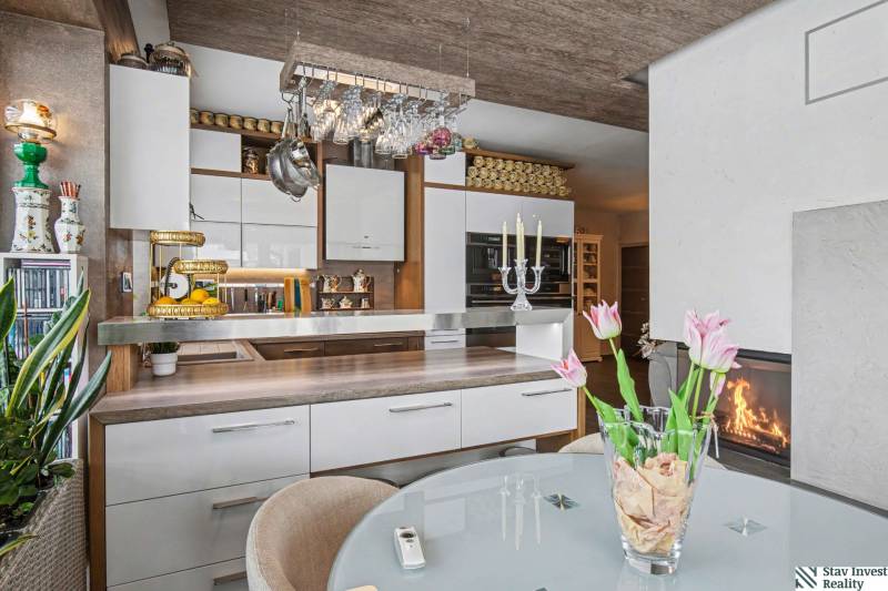 Ideálny dom pre rodinu, Blatné, okr. Senec - Kuchyňa s bielymi skrinkami, barovým pultom a skleneným stolom s kvetmi v rodinnom dome.