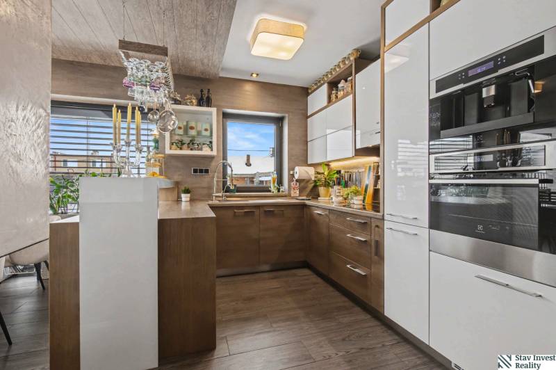 Ideálny dom pre rodinu, Blatné, okr. Senec - Kuchyňa v rodinnom dome s podlahou s dreveným dekorom, modernými spotrebičmi a dekoratívnym osvetlením.