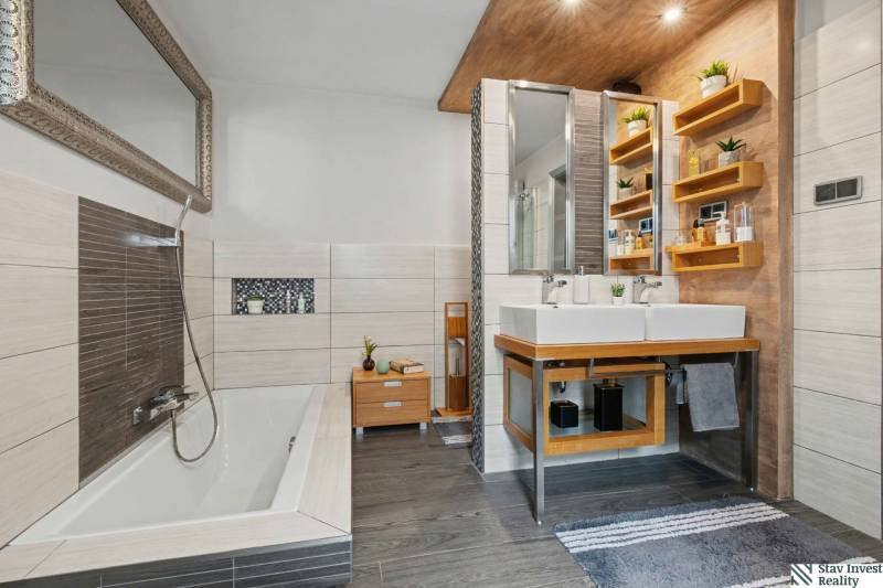 Ideálny dom pre rodinu, Blatné, okr. Senec - Kúpeľňa v rodinnom dome s vaňou, dvoma umývadlami a policami, podlaha s dreveným dekorom.