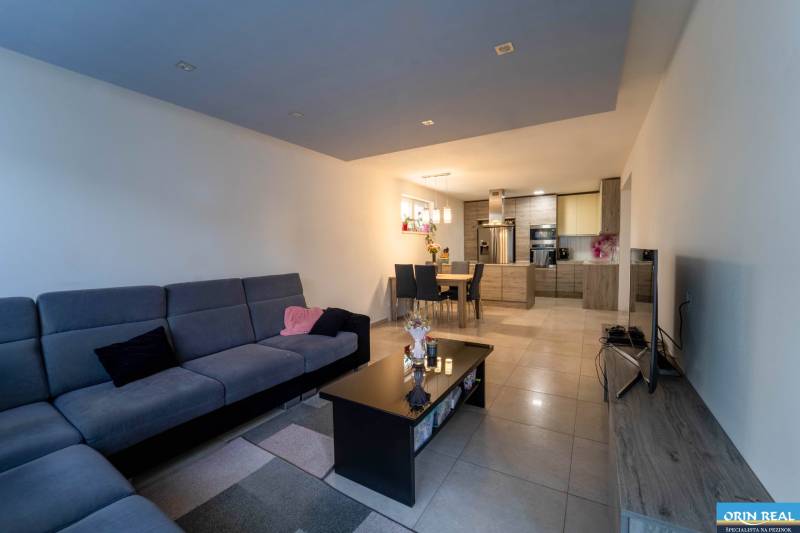 ATRAKTÍVNY 2 IZBOVÝ BYT S VLASTNOU ZÁHRADKOU a 3 parkovacími miestami - Obývacia izba s kuchyňou v 2-izbovom byte, veľká sedacia súprava, jedálenský stôl, dlažba.