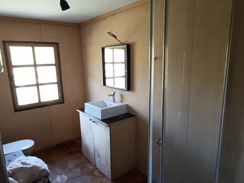 Na predaj záhradná chatka - Kúpeľňa v chate s umývadlom, sprchovacím kútom a podlahou s dreveným dekorom.