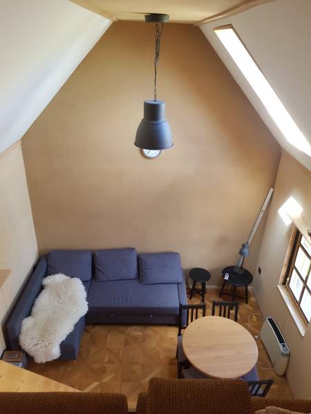 Na predaj záhradná chatka - Chata so sedačkou, jedálenským stolom a podlahou s dreveným dekorom.