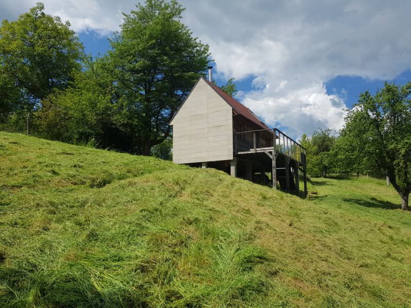 Na predaj záhradná chatka - Chata na ulici Na Gremenici v Žarnovici obklopená zeleným svahom a stromami.