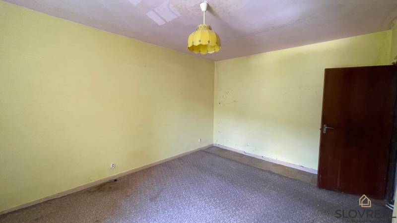 Na predaj veľký 3-izbový byt s lodžiou v Detve - Novosady - Izba v 3-izbovom byte s bledozelenými stenami a žltým lustrom.