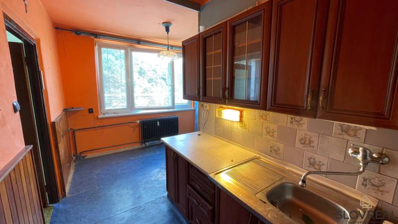 Na predaj veľký 3-izbový byt s lodžiou v Detve - Novosady - Kuchyňa v 3-izbovom byte so skrinkami, umývadlom a obkladačkami s rustikálnym vzorom.