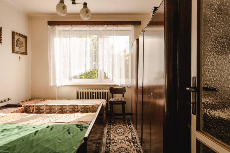 Dvojgeneračný rodinný dom s potenciálom | 2 bytové jednotky, TV - Spálňa v rodinnom dome s oknom, nábytkom a kobercovým dekorom.