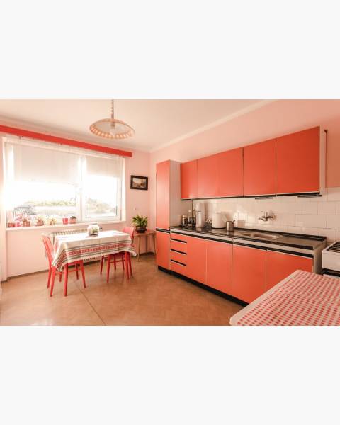 Dvojgeneračný rodinný dom s potenciálom | 2 bytové jednotky, TV - Kuchyňa v rodinnom dome s oranžovými skrinkami a podlahou s dreveným dekorom.