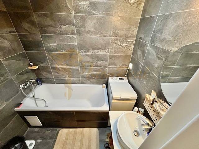 Veľký 2-izb. byt v tehlovom dome, Ružová dolina, Ružinov časť Nivy - Kúpeľňa v 2-izbovom byte s vaňou, umývadlom a tmavými obkladmi stien.