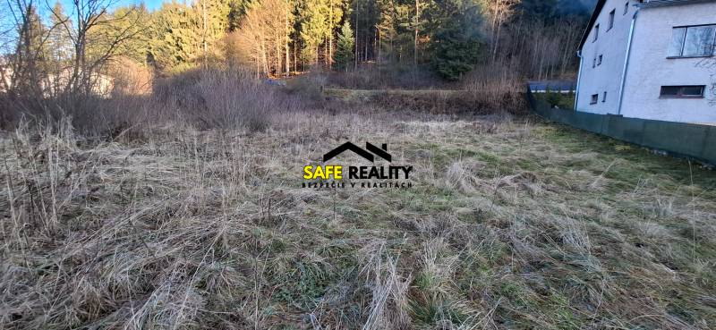 Stavebný pozemok Svrčinovec - Pozemky - bývanie v Svrčinovci s trávnatým porastom a blízkosťou lesa a budovy.