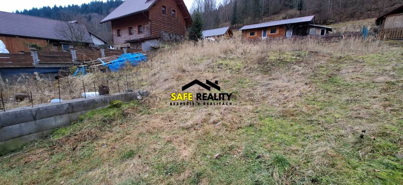 Lukratívny stavebný pozemok - Pozemok v Oščadnici určený na bývanie s viditeľnými drevenými stavbami na svahovitom teréne.