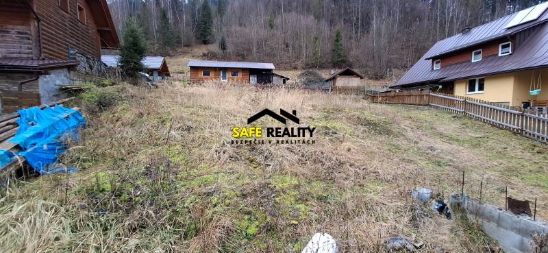 Lukratívny stavebný pozemok - Pozemok na bývanie v Oščadnici, s drevenicou a lesnou kulisou v pozadí.