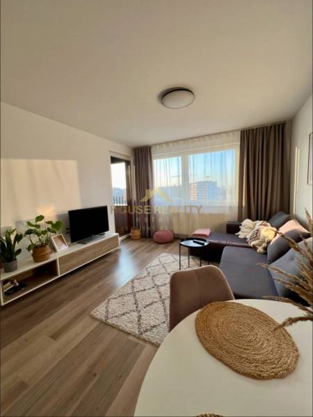 Novostavba FUXOVA 2 izbový byt, parking, Bosákova ul., BA V. Petržalka - Obývacia izba so sedačkou, televízorom a podlahou s dreveným dekorom v 2-izbovom byte.