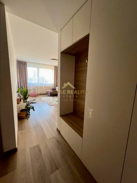 Novostavba FUXOVA 2 izbový byt, parking, Bosákova ul., BA V. Petržalka - Chodba v 2-izbovom byte s podlahou s dreveným dekorom a svetlým nábytkom.