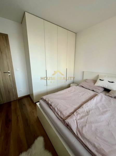 Novostavba FUXOVA 2 izbový byt, parking, Bosákova ul., BA V. Petržalka - Spálňa v 2-izbovom byte s posteľou, šatníkovou skriňou a podlahou s dreveným dekorom.