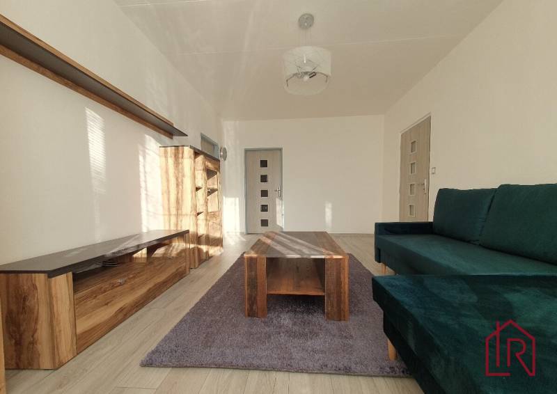 KH-1052, 3 izbový byt, Košice – Staré Mesto, širšie centrum, Kuzmányho - Obývacia izba v 3-izbovom byte s pohovkou, skriňou a stolíkom na podlahe s dreveným dekorom.