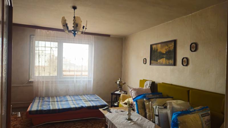 Predaj 4 izbový rodinný dom Šulekovo  - Izba v rodinnom dome s posteľou, lustrom, tabuľami a pohovkou.