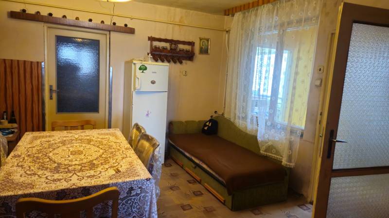Predaj 4 izbový rodinný dom Šulekovo  - Kuchyňa v rodinnom dome s obrusom na stole, pohovkou a chladničkou.