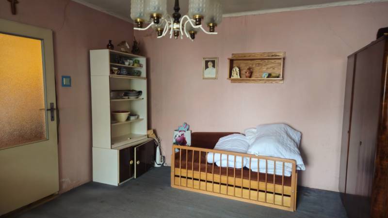 Predaj 4 izbový rodinný dom Šulekovo  - Izba s posteľou, policami s riadmi a závesným svietidlom v rodinnom dome.