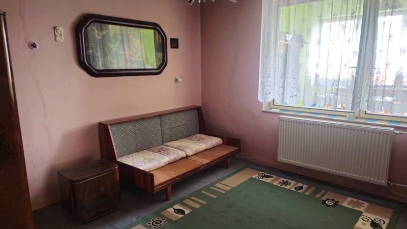 Predaj 4 izbový rodinný dom Šulekovo  - Izba v rodinnom dome s pohovkou, zeleným kobercom a ornamentálnou záclonou.