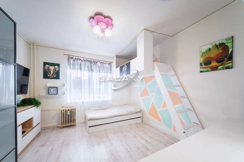 Kompletne zrekonštruovaný 3-izbový byt s balkónom – Rimavská Sobota - Detská izba v 3-izbovom byte s farebnou stenou a podlahou s dreveným dekorom.