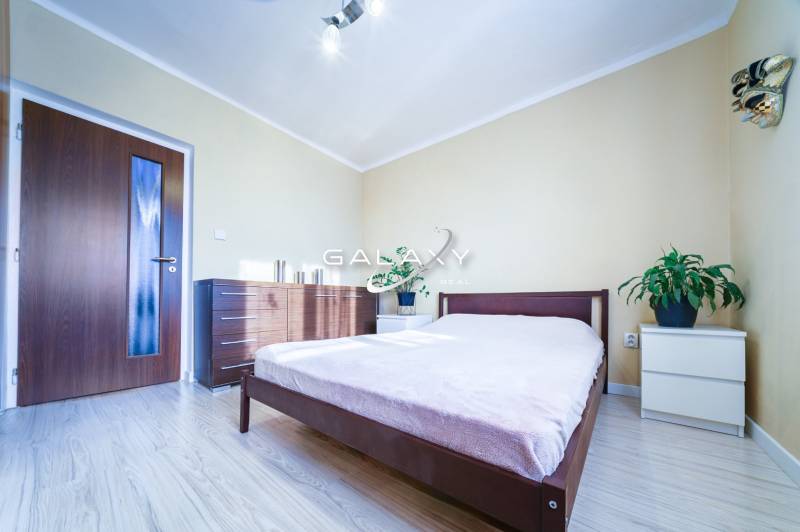 Kompletne zrekonštruovaný 3-izbový byt s balkónom – Rimavská Sobota - Spálňa v 3-izbovom byte s posteľou, komodou a podlahou s dreveným dekorom.