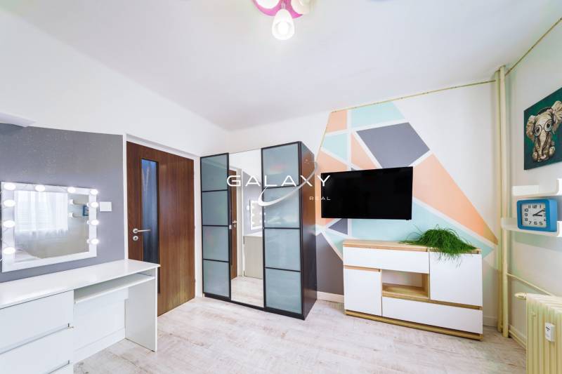 Kompletne zrekonštruovaný 3-izbový byt s balkónom – Rimavská Sobota - Farebná geometrická stena, zrkadlová skriňa, TV a stolík v 3-izbovom byte.