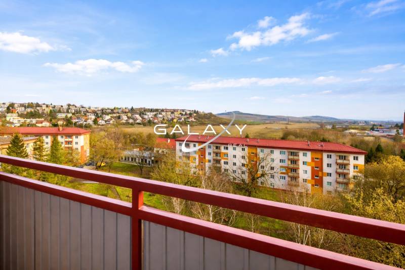 Kompletne zrekonštruovaný 3-izbový byt s balkónom – Rimavská Sobota - Výhľad z 3-izbového bytu na Rožňavskej ulici v Rimavskej Sobote so zeleňou a oblohou.