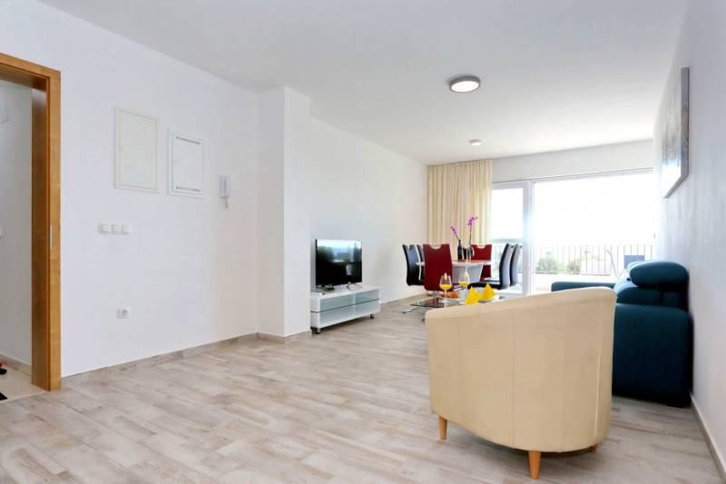 CHORVÁTSKO - VÝBORNÁ PONUKA! - 3-izbový apartmán - SUKOŠAN, Zadar - Obývacia izba v 3-izbovom byte s podlahou s dreveným dekorom a jedálenským stolom.