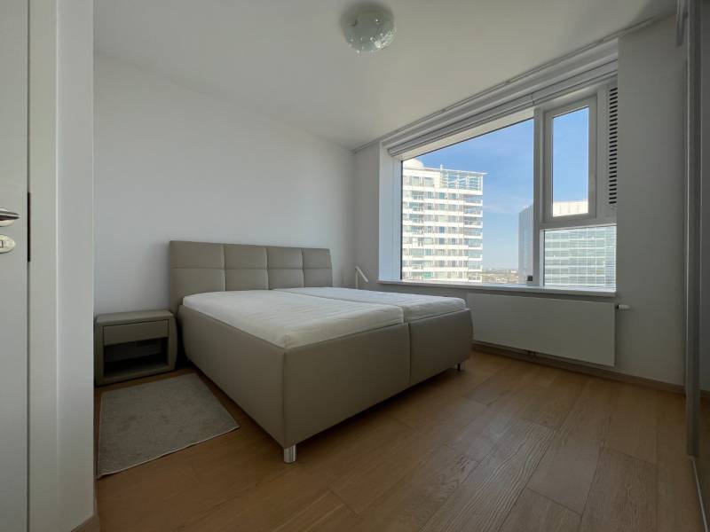 NUERA︱PANORAMA CITY- Veľký 3-izbový byt s výhľadom na hrad - Spálňa v 3-izbovom byte s posteľou, nočným stolíkom a podlahou s dreveným dekorom.