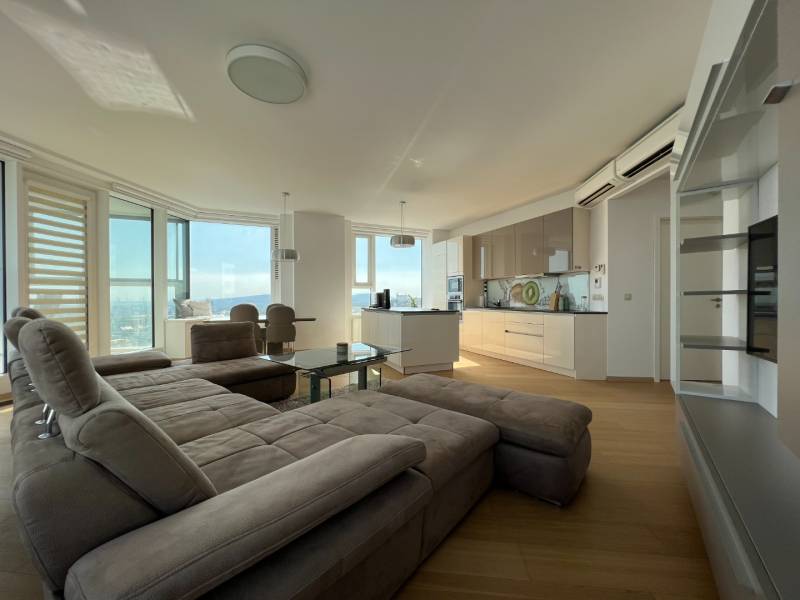 NUERA︱PANORAMA CITY- Veľký 3-izbový byt s výhľadom na hrad - Obývacia izba s kuchyňou a podlahou s dreveným dekorom v 3-izbovom byte.