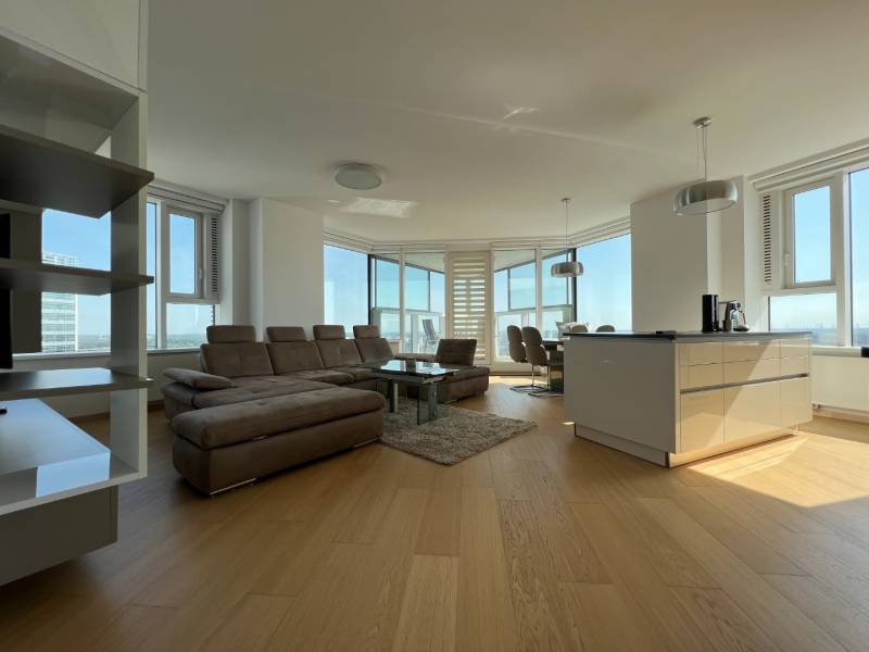 NUERA︱PANORAMA CITY- Veľký 3-izbový byt s výhľadom na hrad - Svetlý 3-izbový byt s podlahou s dreveným dekorom, veľkými oknami a priestrannou sedacou súpravou.