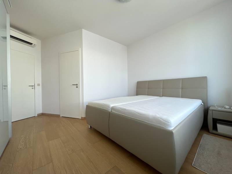 NUERA︱PANORAMA CITY- Veľký 3-izbový byt s výhľadom na hrad - Spálňa so svetlou posteľou, nočným stolíkom a podlahou s dreveným dekorom v 3-izbovom byte.