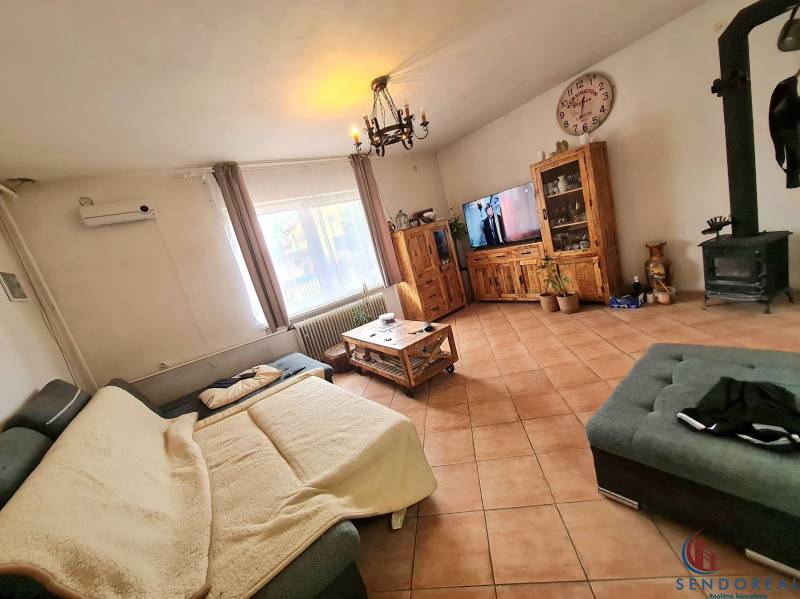 5.izb RD Čereňany pozemok 1028m - Obývacia izba s krbovými kachľami, dlažbou a dreveným nábytkom v rodinnom dome.