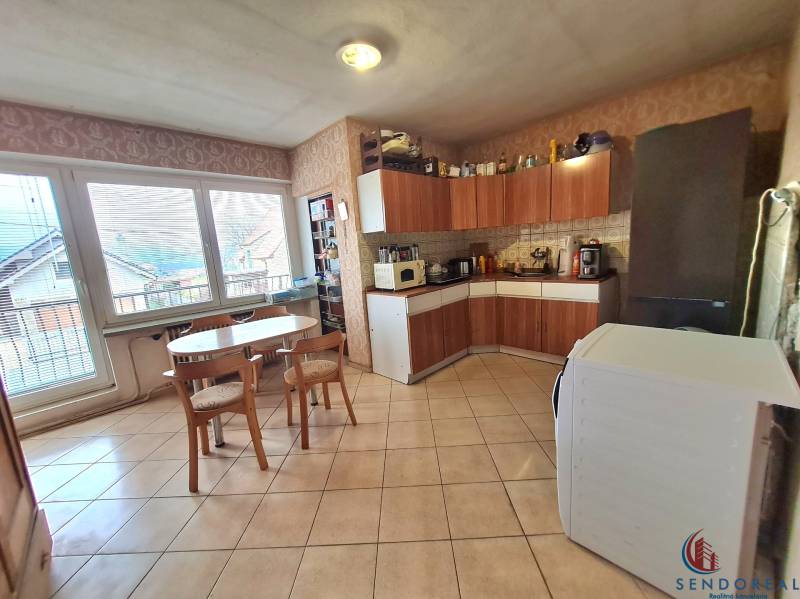 5.izb RD Čereňany pozemok 1028m - Kuchyňa v rodinnom dome s nábytkom z dreveným dekorom, jedálenským stolom a spotrebičmi.