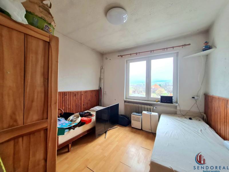 5.izb RD Čereňany pozemok 1028m - Interiér rodinného domu s podlahou s dreveným dekorom, posteľami a výhľadom z okna.