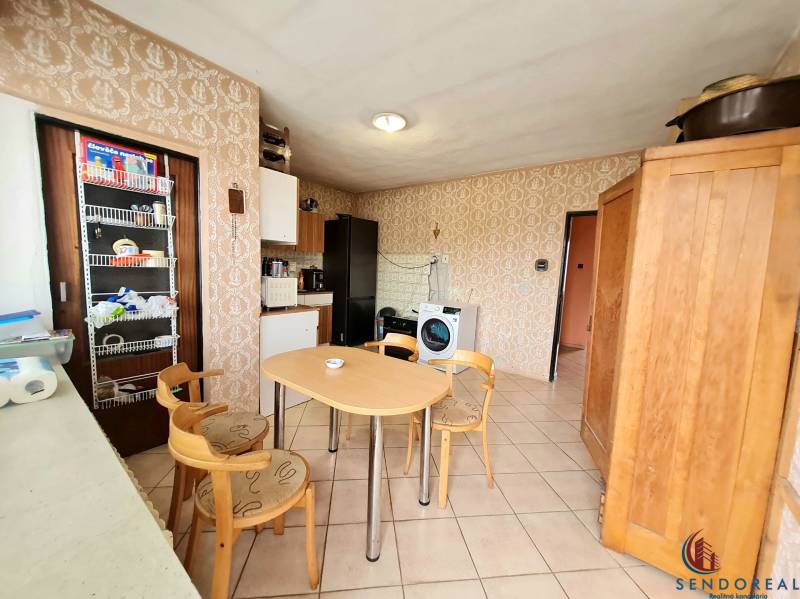 5.izb RD Čereňany pozemok 1028m - Kuchyňa v rodinnom dome s jedálenským stolom, tapetami a vstavanými skrinkami.