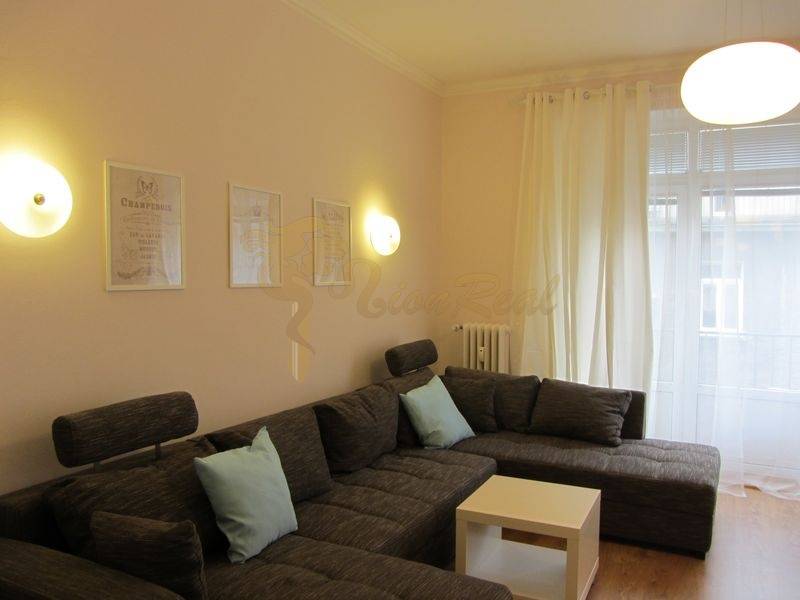 4-izb.byt v centre mesta, Obchodná ul., BA I - Staré Mesto, 2 x balkón - Pohodlná sivá sedacia súprava v obývačke 4-izbového bytu s bielymi záclonami.