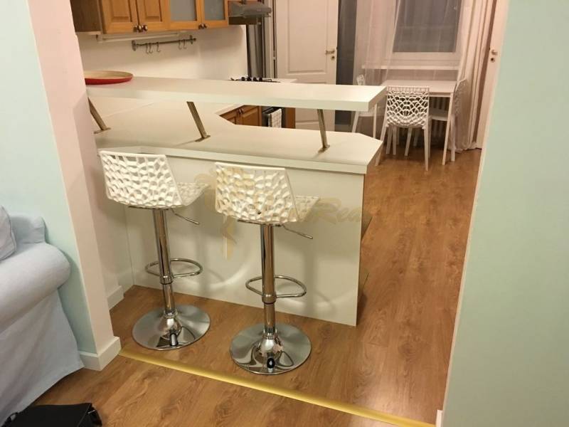 4-izb.byt v centre mesta, Obchodná ul., BA I - Staré Mesto, 2 x balkón - Kuchynský pult s dvoma barovými stoličkami a podlahou s dreveným dekorom v 4-izbovom byte.