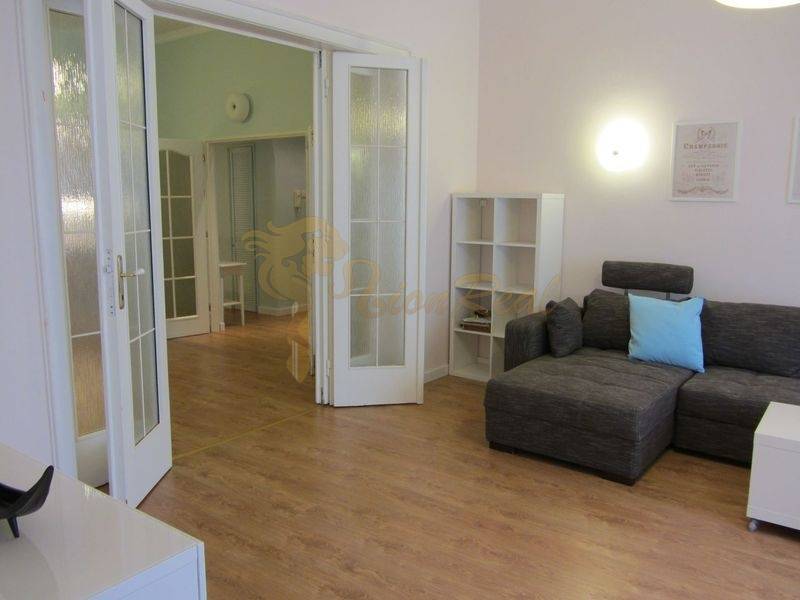 4-izb.byt v centre mesta, Obchodná ul., BA I - Staré Mesto, 2 x balkón - Svetlá obývačka v 4-izbovom byte s rohovou sedačkou a podlahou s dreveným dekorom.