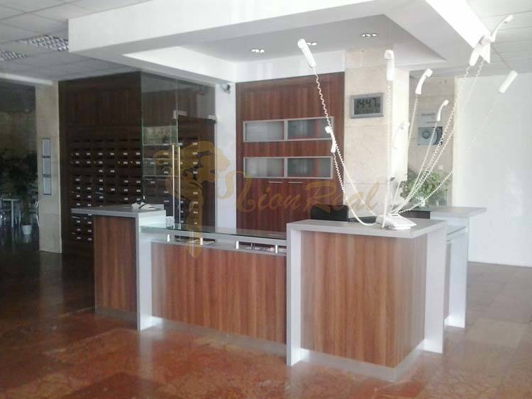 Kancelárie, Drieňová ul., Ružinov 25 m2 - Recepčný pult v kancelárii s drevenými detailmi a moderným osvetlením.